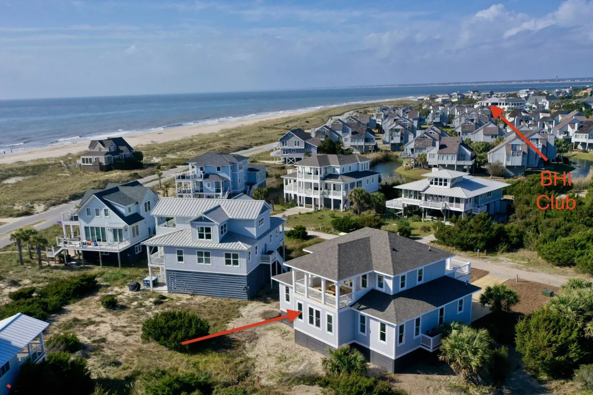 A broad exterior view showcasing the ocean, nearby beach, and spacious property surrounded by other upscale homes. The expansive setting suggests proximity to the best of Bald Head Island, including community amenities and club access.
