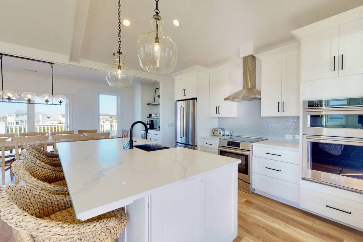A modern kitchen with a large granite island, pendant lighting, sleek appliances, and bar stools. The layout is ideal for both cooking and socializing, with the island serving as the focal point for culinary activities and casual gatherings.